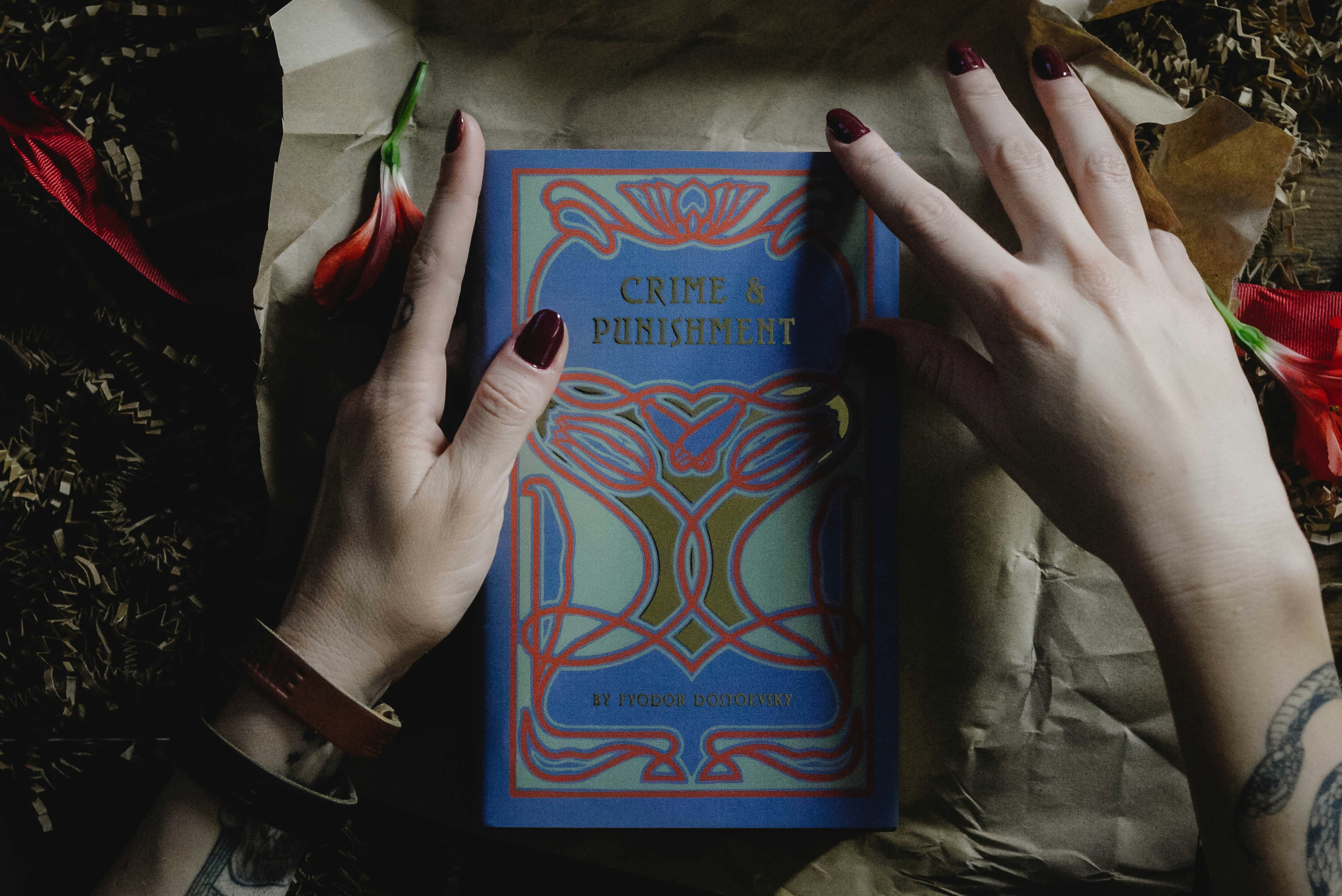 Photo of a pair of female hands with dark nail polish holding a copy of Dostoevsky's "Crime and punishment". 